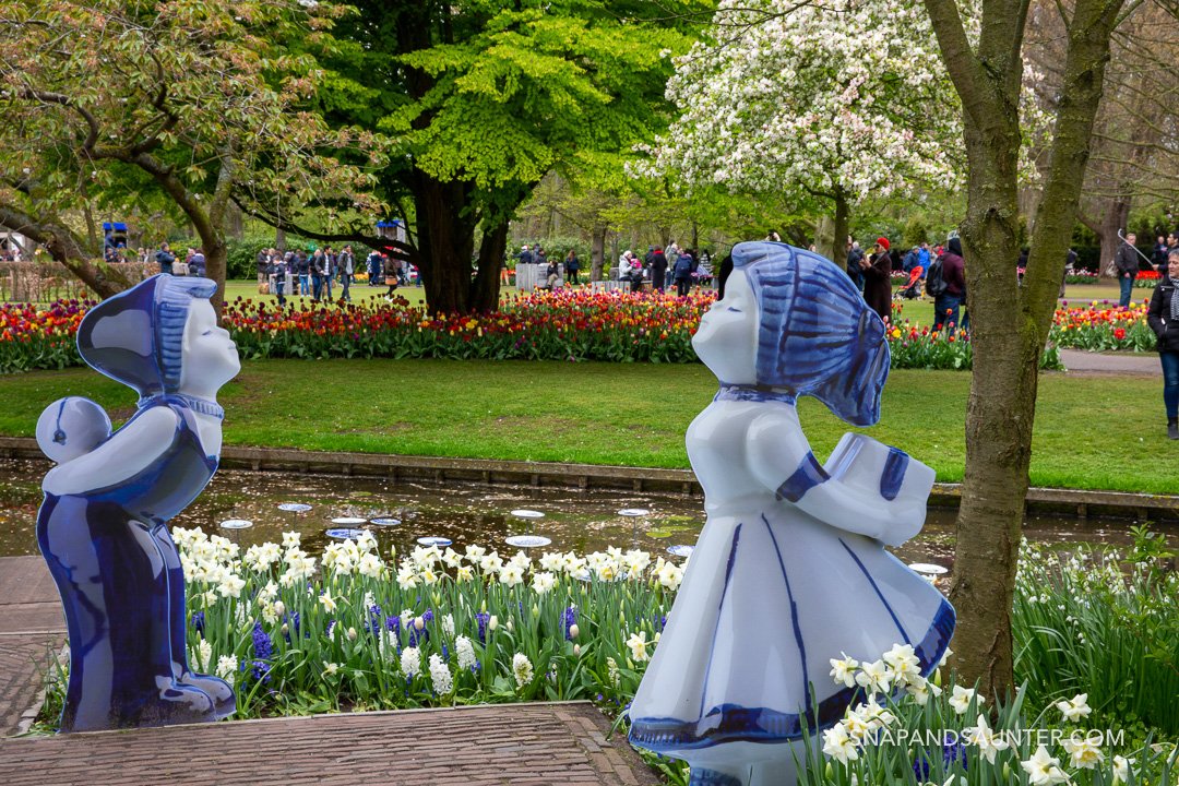 dutch statues with tulips in the background in Keukenhof Gardens in Holland